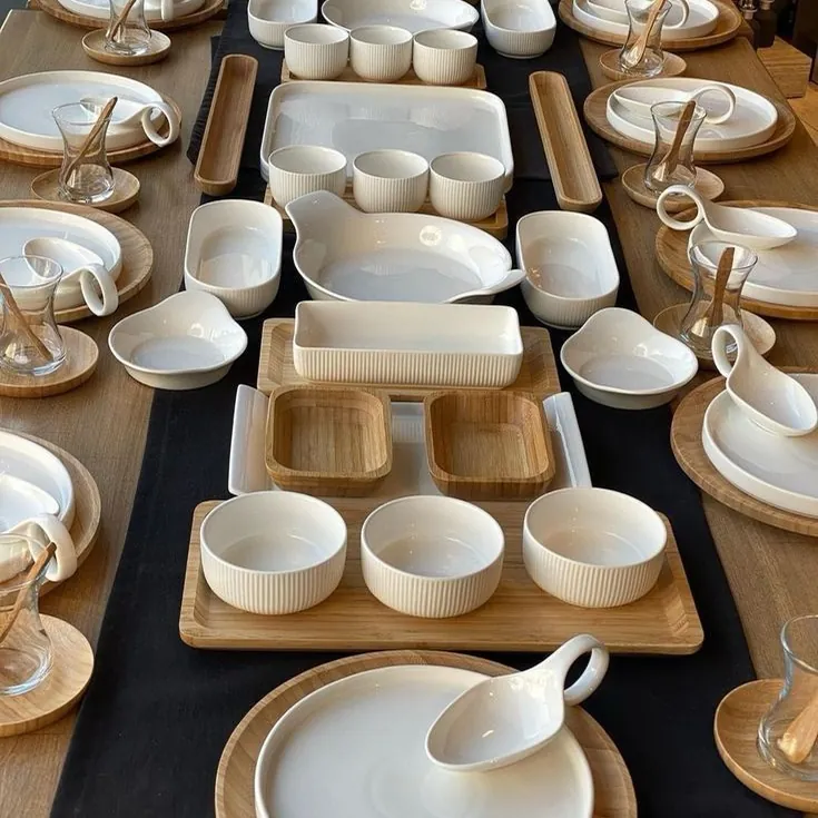 Longue table de buffet avec plats, ramequins et plateaux blancs sur chemin de table noir
